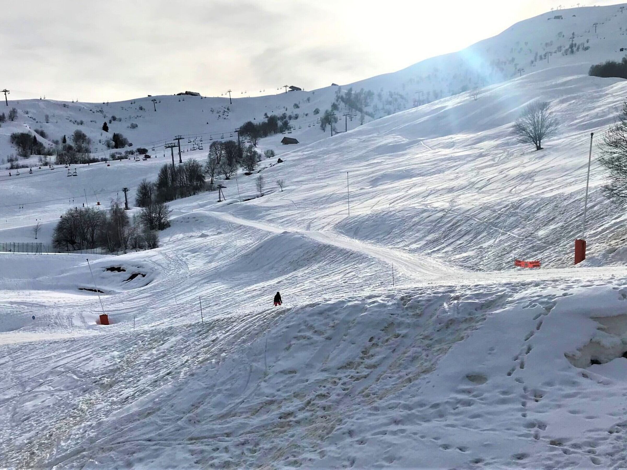 A snowy ski slope with ski lifts and a person skiing.