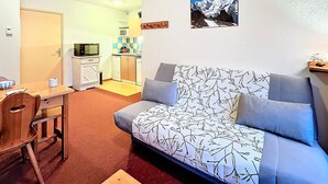 Een knus woongedeelte met een bank, een eettafel en een kitchenette.