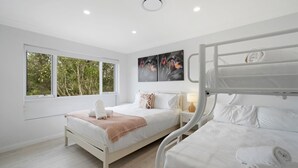 Un dormitorio moderno con un ventanal grande, una cama litera, una mesita de noche con lámpara y una obra de arte en la pared.