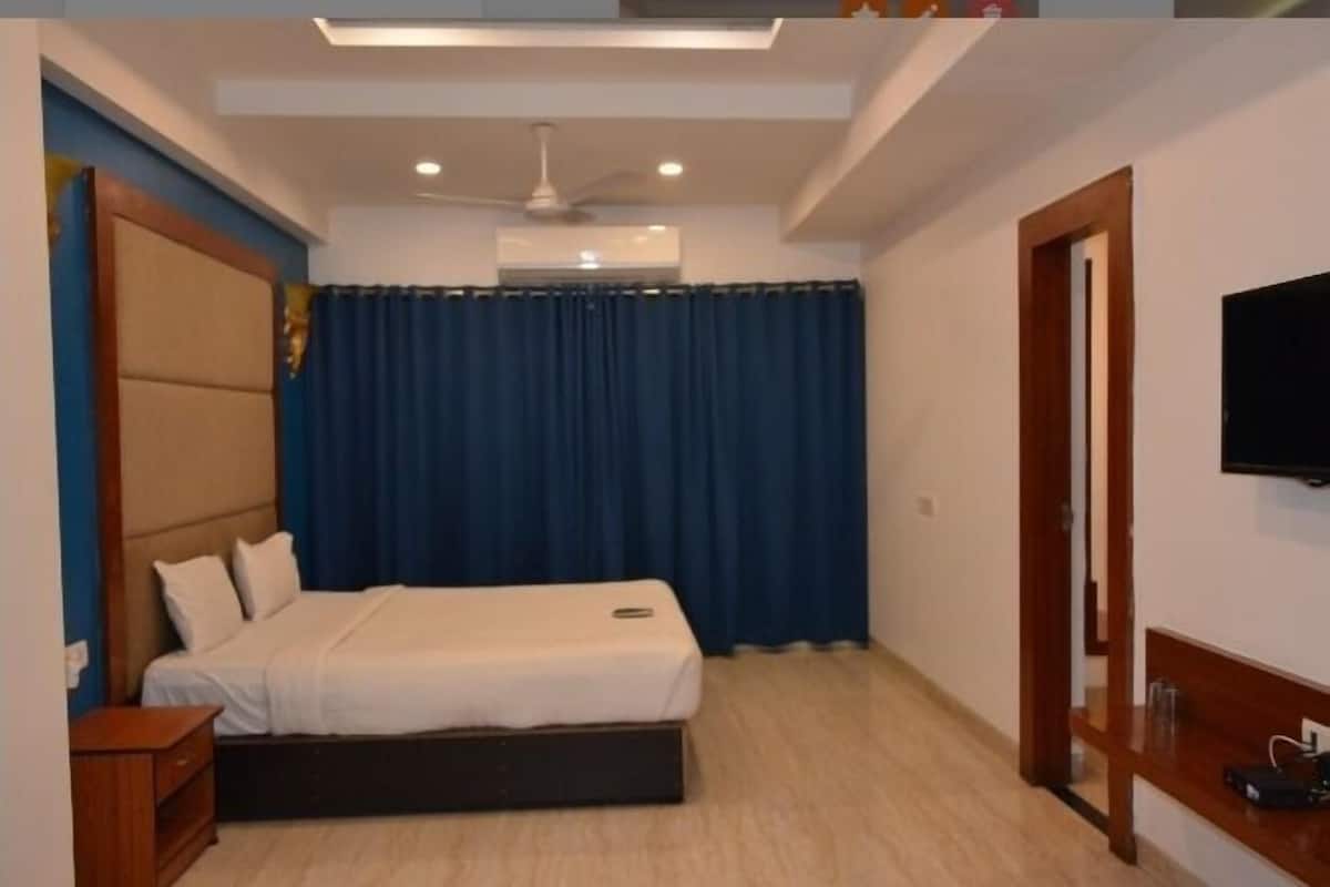 A bedroom with a bed, a nightstand, a TV, and a ceiling fan.
