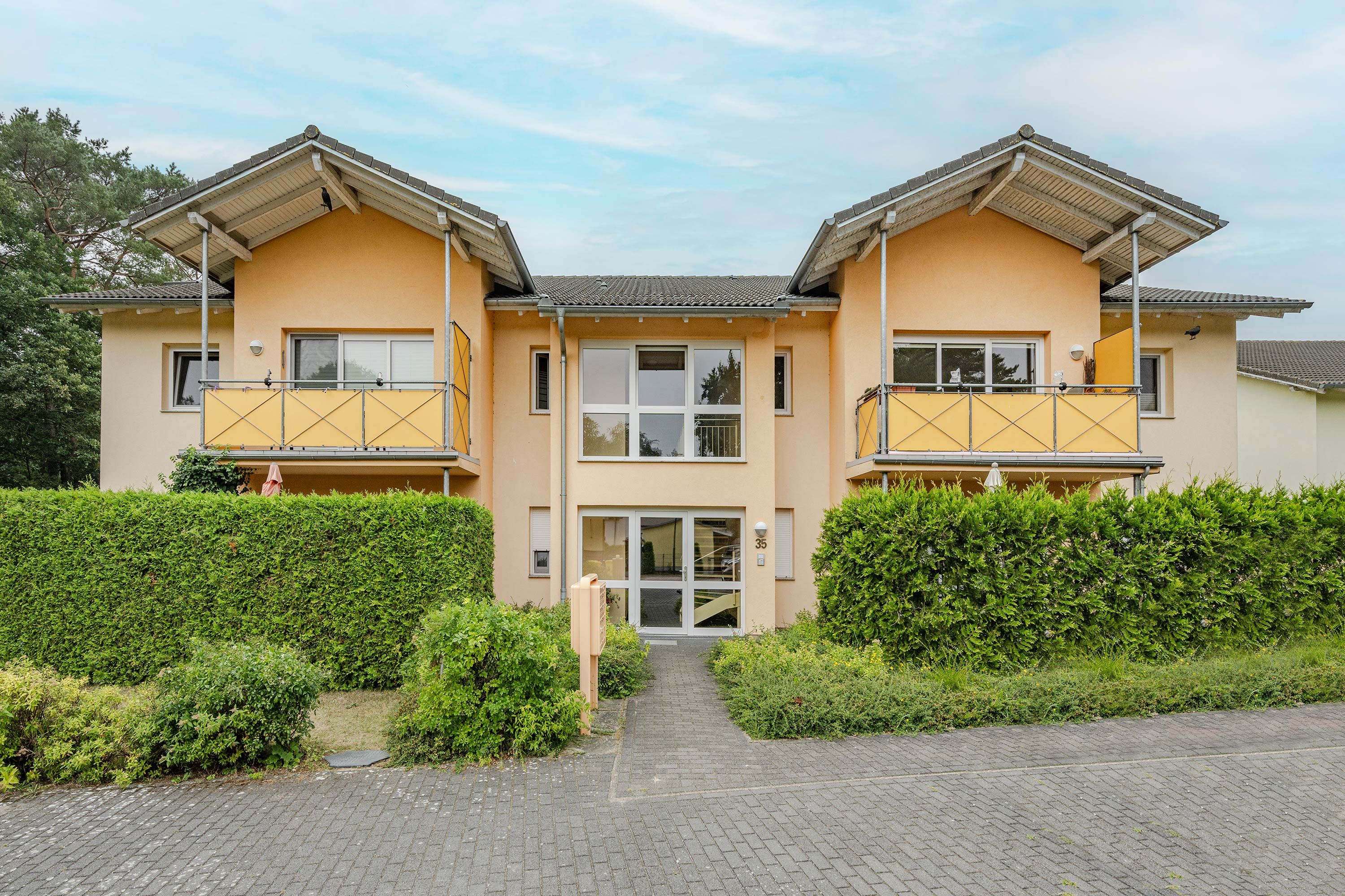 Un edificio residenziale a due piani con facciata simmetrica, ampie finestre e un ingresso centrale.
