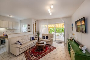 Un salon moderne avec un canapé, des fauteuils, une table basse et une vue sur l’extérieur.