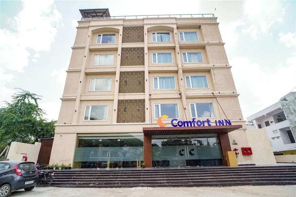Un hotel de varios pisos con fachada color crema, ventanas grandes y un letrero que dice "Comfort Inn".
