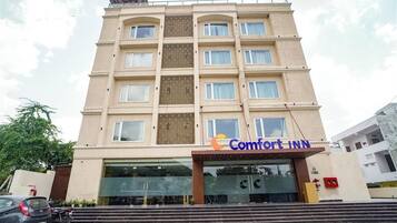 Un hotel de varios pisos con fachada color crema, ventanas grandes y un letrero que dice "Comfort Inn".