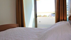 A hotel room with a bed, curtains, and a view through a window. - Beautiful 3-room apartment with terrace and parking in Villeneuve-Loubet Plage (Villeneuve-Loubet)