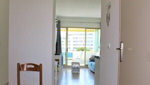 A hallway leading to a balcony with a view of a building and a chair in the foreground. - Beautiful 3-room apartment with terrace and parking in Villeneuve-Loubet Plage (Villeneuve-Loubet)