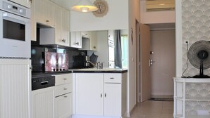 A modern kitchen with white cabinetry, a built-in oven, and a coffee maker. - Beautiful 3-room apartment with terrace and parking in Villeneuve-Loubet Plage (Villeneuve-Loubet)