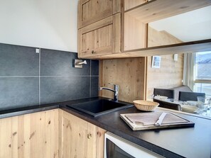 A modern kitchen with wooden cabinets, a black countertop, and a large window.