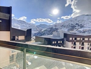 A modern building with a glass balcony overlooking a snowy mountain range.