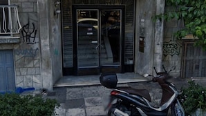 Entrada de un edificio con una scooter estacionada adelante.