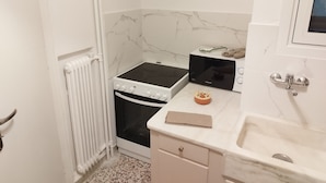 Una cocina compacta con estufa, microondas y lavabo.