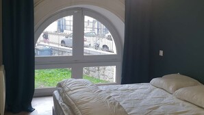 A bedroom with a large arched window, a bed with white bedding, and a geometric light fixture. - City center apartment - 10/12 guests (Cauterets)