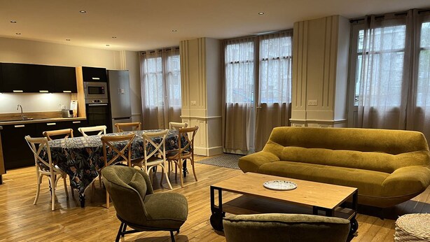 A modern living room with a sofa, chairs, a dining table, and a kitchen area with appliances. - City center apartment - 10/12 guests (Cauterets)