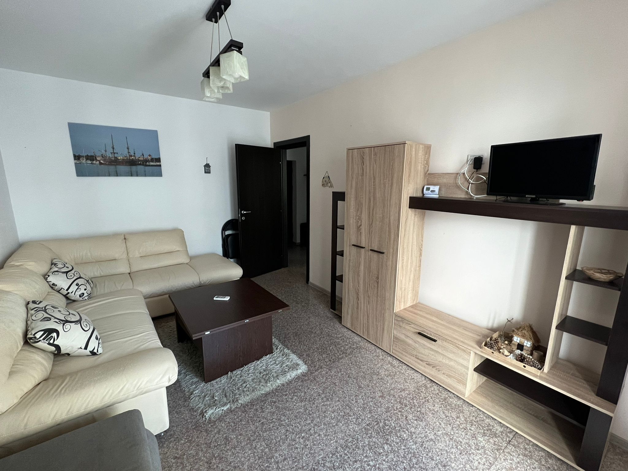 A modern living room with a sofa, coffee table, TV stand, and wardrobe.