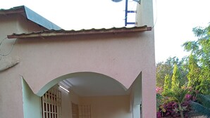 A house with a covered patio, a table and chairs, and a window with bars.