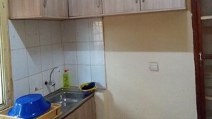 A kitchen with light wooden cabinets, a sink, and a blue basin.