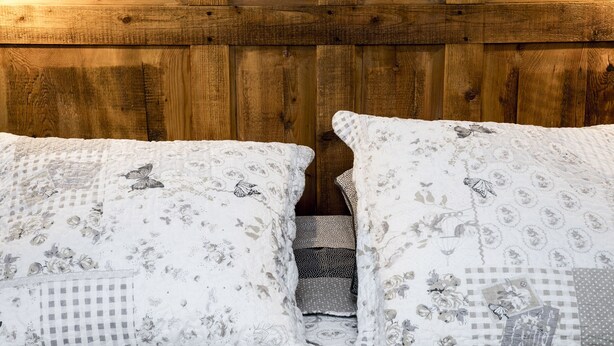 A bed with floral patterned bedding and a wooden headboard. - Spacious 6-person gîte in Kaysersberg (Kaysersberg)