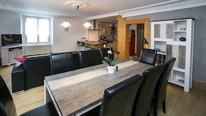 A dining area with a wooden table, black chairs, and a potted plant. There is a kitchen in the background with wooden cabinets and a red refrigerator. - Spacious 6-person gîte in Kaysersberg (Kaysersberg)