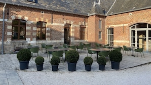 En innergård med utomhusmöbler, tegelväggar och planterade blommor i krukor.