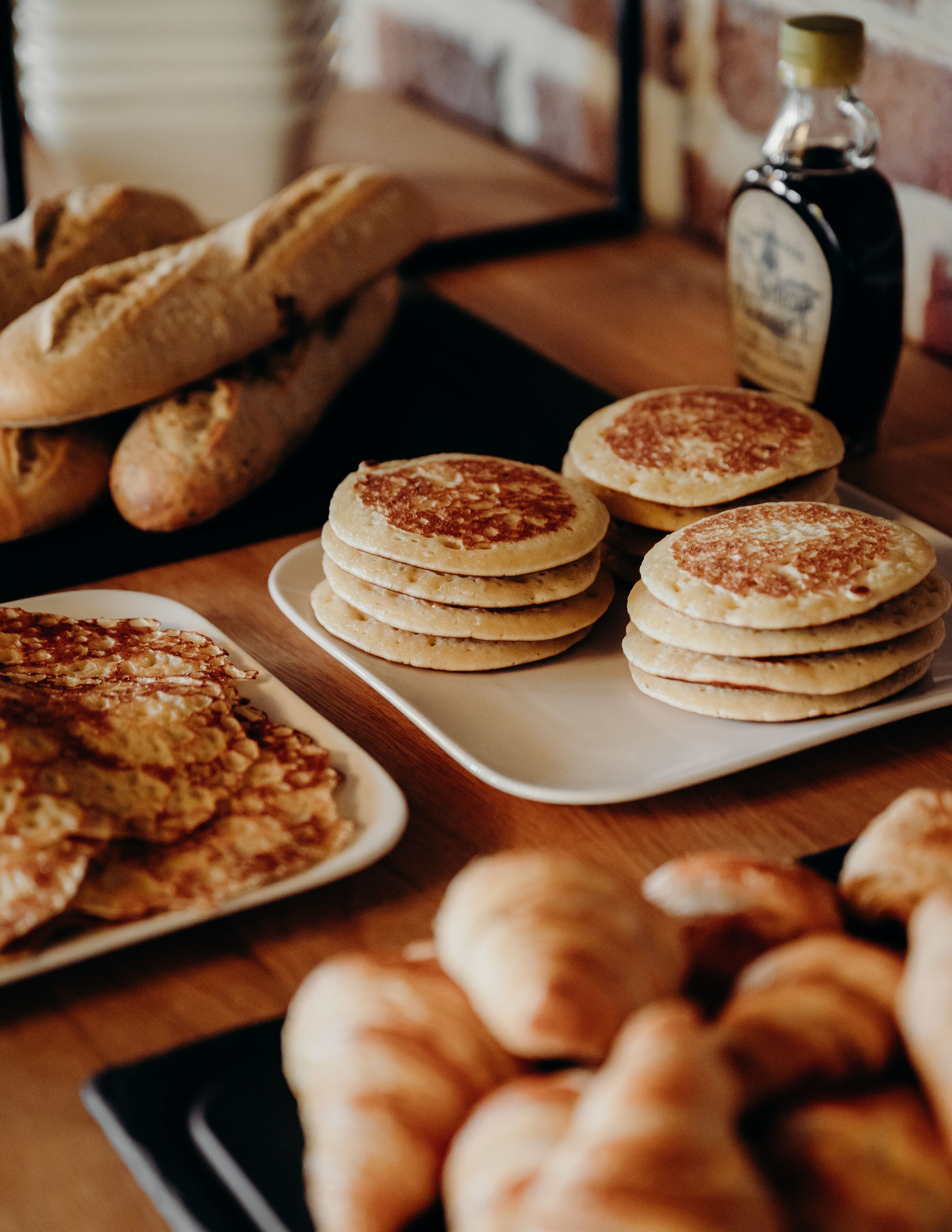 Un tavolo con diversi prodotti da forno, tra cui pancake, pane e dolci.