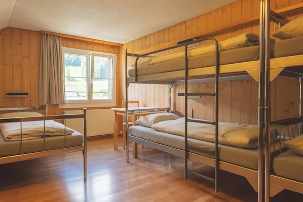 Habitación con literas, paredes de madera y una ventana.