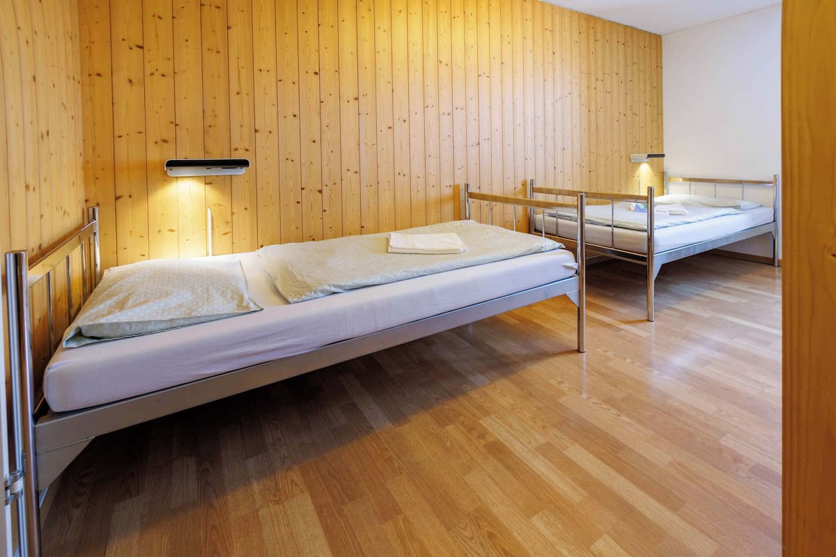 A room with two single beds, wooden walls, and a wooden floor.