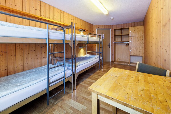 A bunk bed room with a wooden table and a chair. - Youth Hostel Engelberg (Engelberg)