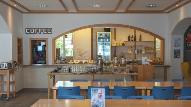 A coffee shop interior with a counter, seating area, and visible coffee-making equipment. - Youth Hostel Engelberg (Engelberg)