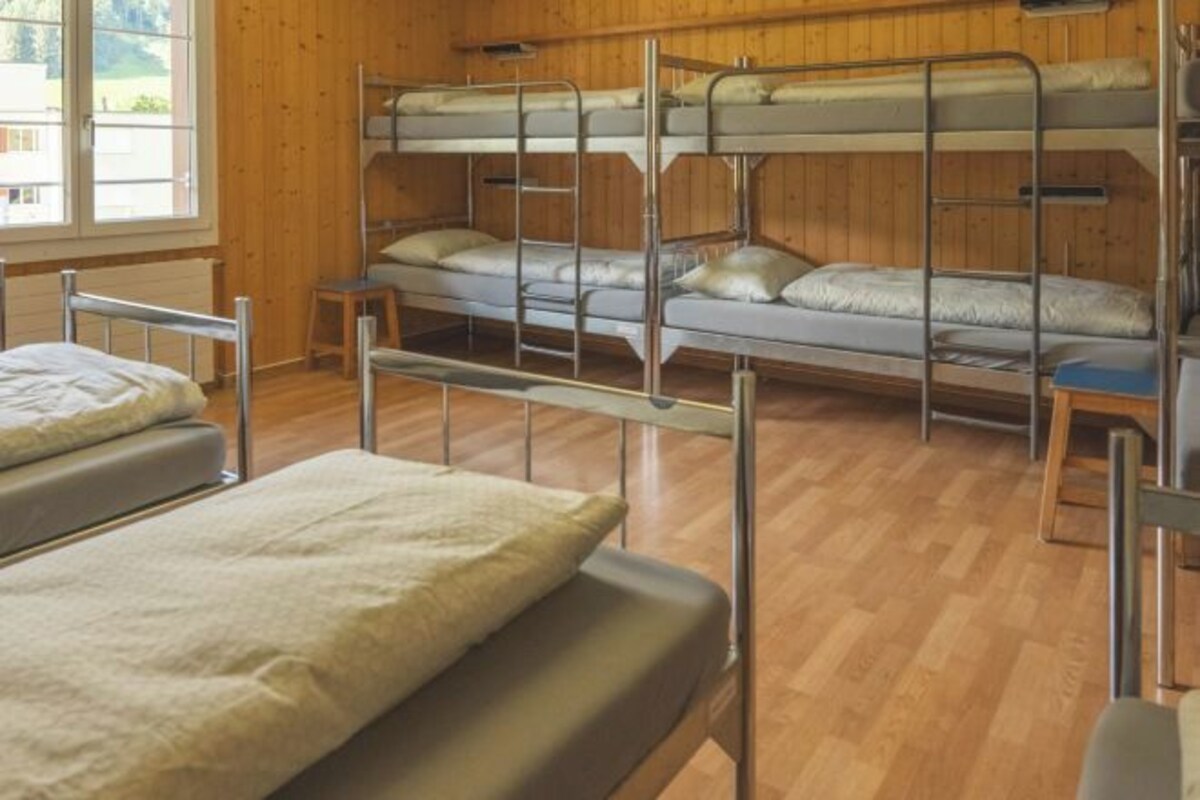 Habitación con literas, paredes de madera y una ventana.
