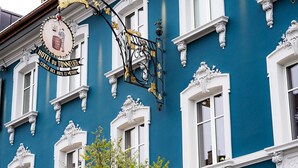 A blue building with white window frames and a sign that reads "HOTEL DU TONNELIER." - Le Tonnelier (Bulle)