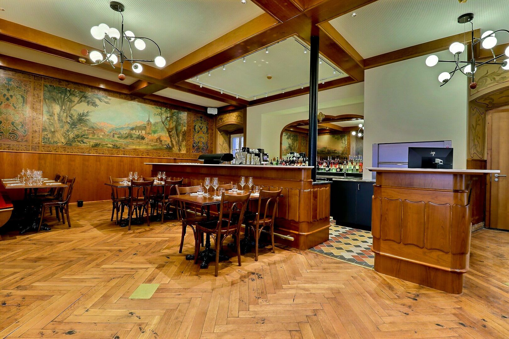 Un restaurante con pisos de madera, una zona de bar y un mural en la pared.