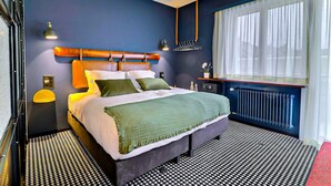 A modern bedroom with a bed, bedside lamps, a radiator, and a window with curtains. - Le Tonnelier (Bulle)