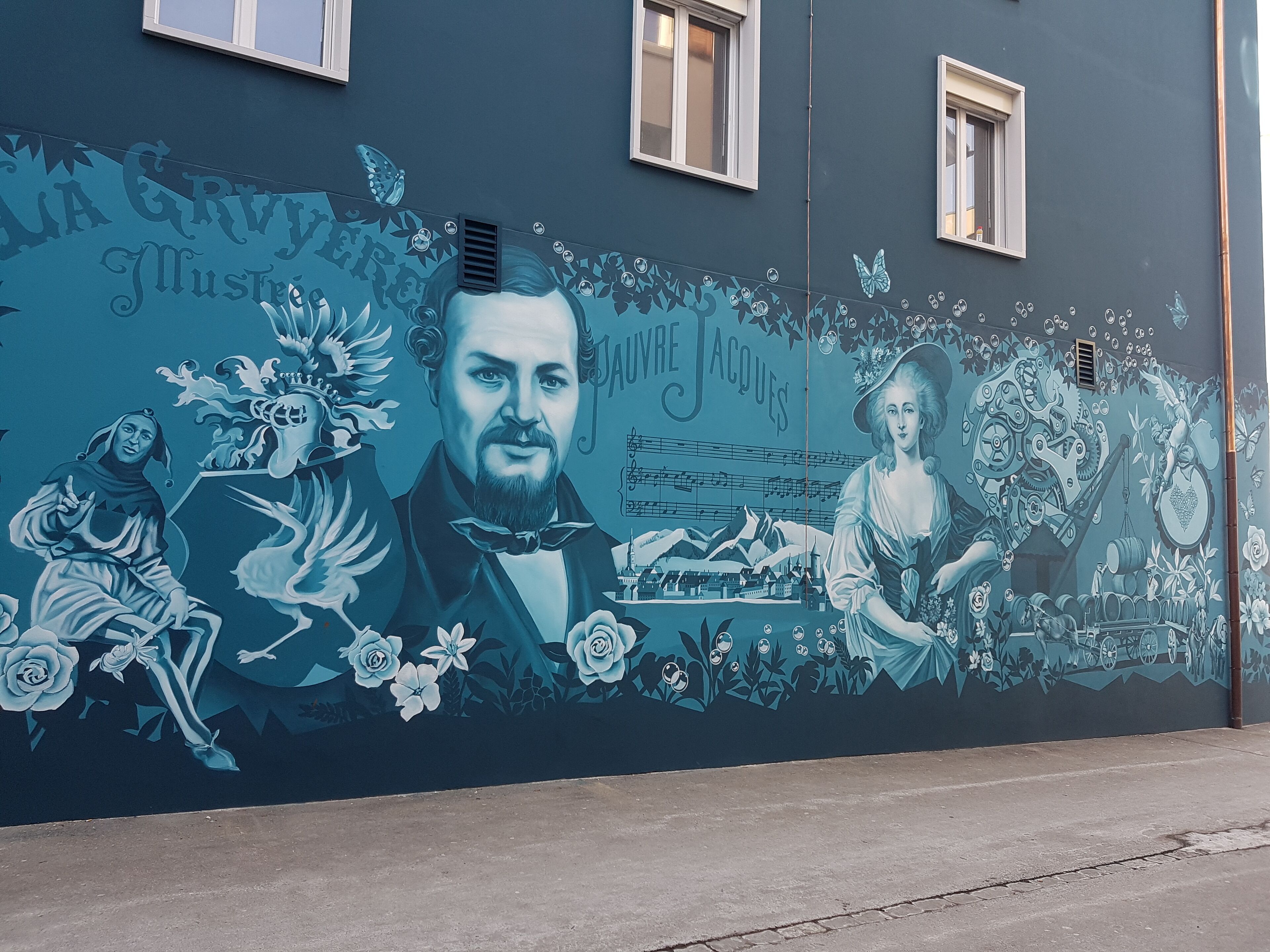 Une fresque ornant un bâtiment, représentant un homme et une femme, avec des motifs floraux et mécaniques.