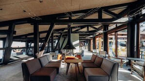 Amplia sala de estar con sofás de cuero, una mesa redonda y grandes ventanales con vistas al exterior.