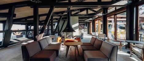 Un vaste espace salon doté de canapés en cuir, d’une table ronde et de grandes fenêtres offrant une vue sur l’extérieur.