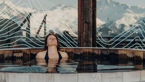 Una persona en un jacuzzi con montañas al fondo.
