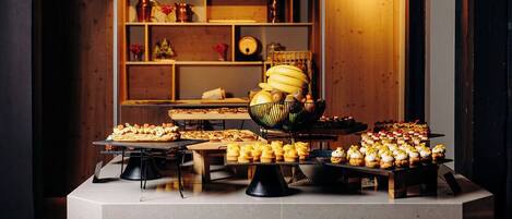 A buffet setup with various food items and a decorative shelf in the background.