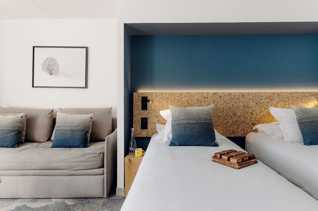 Una habitación de hotel con una cama grande, un sofá y un cuadro en la pared.