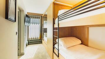 Une chambre avec un lit superposé, une fenêtre, un radiateur et une porte donnant sur une autre pièce.