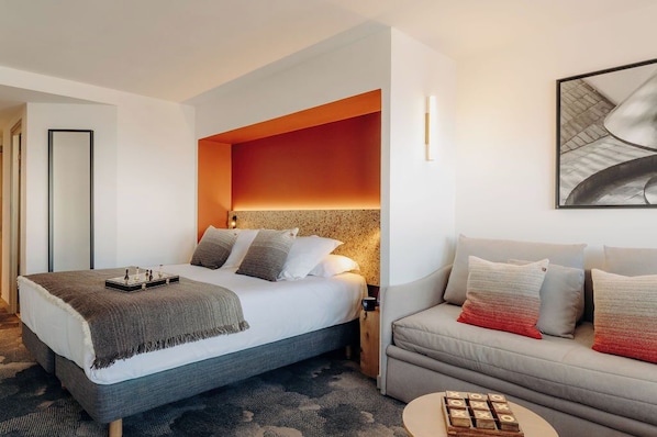 Una habitación de hotel moderna con una cama grande, un sofá y una mesita de café.