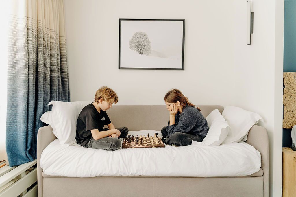 Deux personnes sont assises sur un lit et jouent aux échecs.