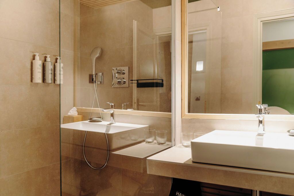 Une salle de bain moderne avec deux vasques, une douche à l’italienne et un grand miroir.