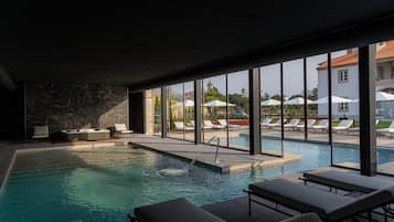 Een binnenzwembad, een buitenzwembad en parasols bij het zwembad