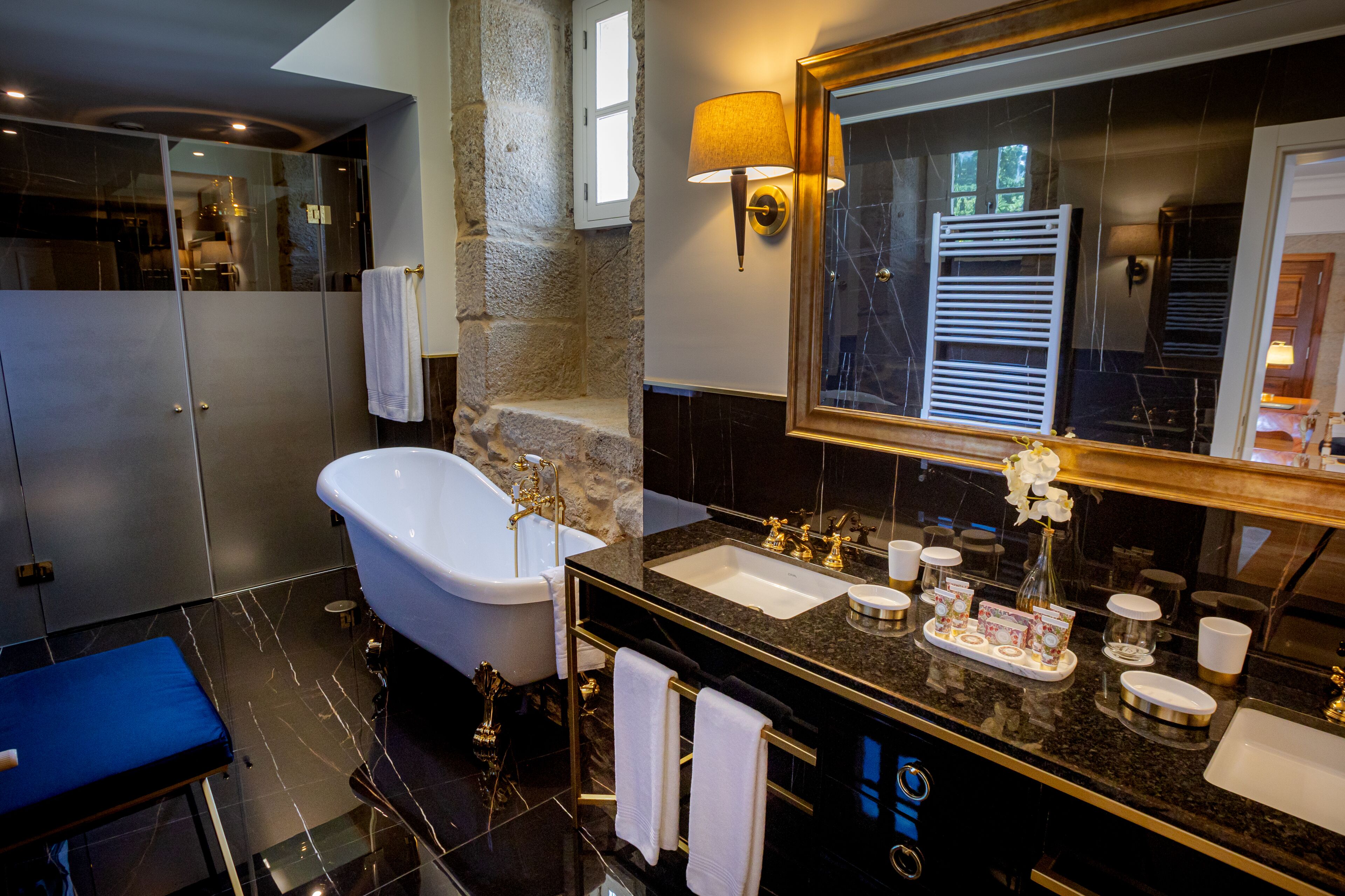 Un baño moderno con una bañera independiente, un espejo grande y un tocador con encimera de mármol.