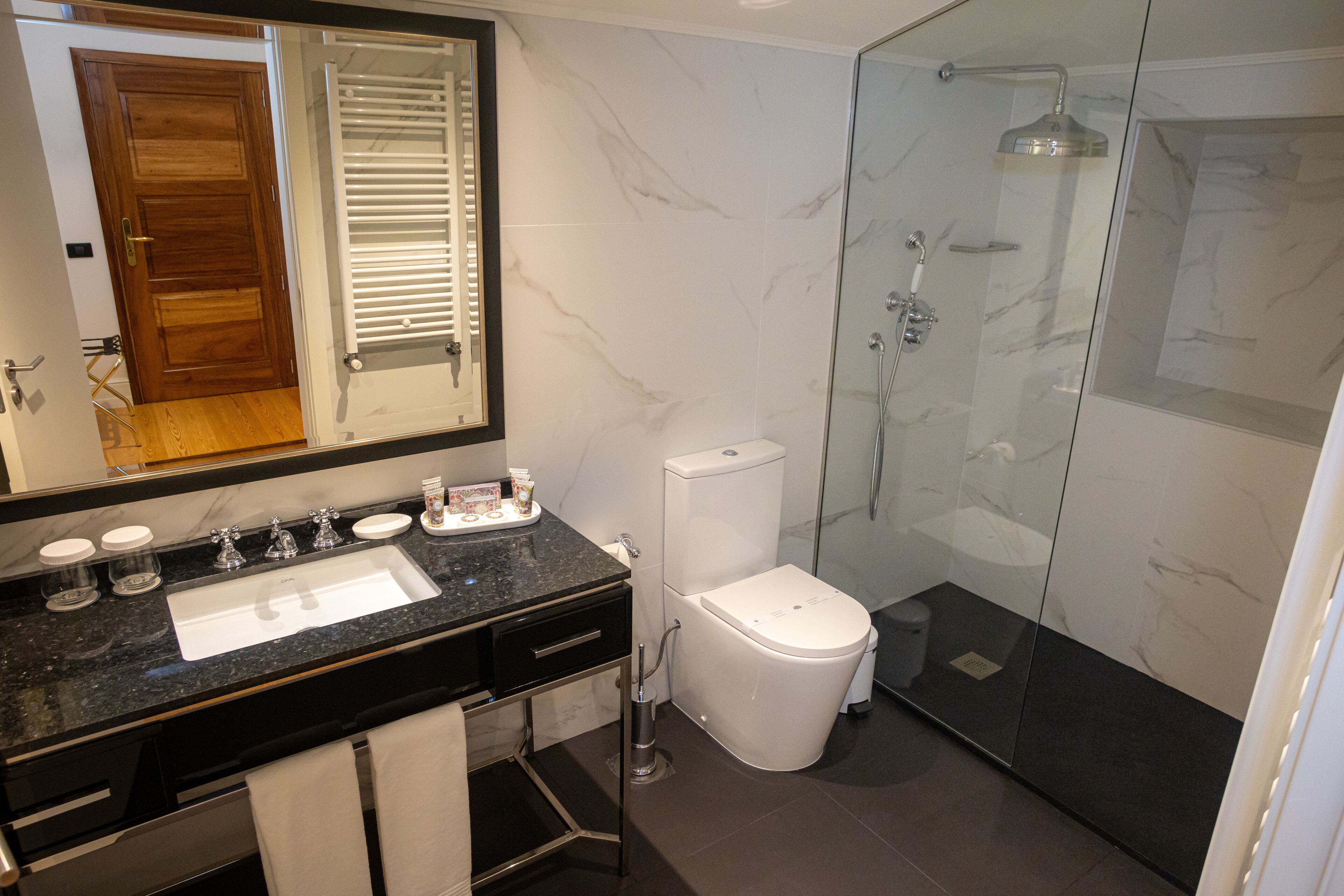 A modern bathroom with a marble sink, toilet, and glass-enclosed shower.