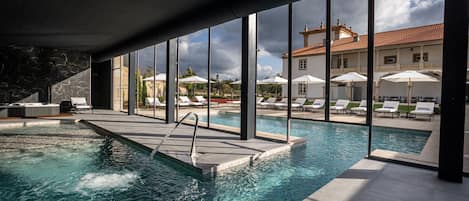 Una piscina cubierta, una piscina al aire libre, sombrillas, tumbonas