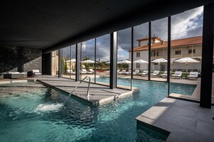 Una piscina techada, una piscina al aire libre, sombrillas