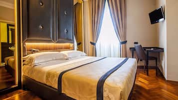 Quarto de hotel com uma cama grande, uma mesa, uma cadeira, uma televisão e um banheiro com espelho e pia.