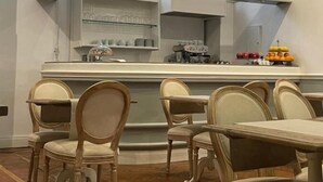 Une cuisine moderne avec un comptoir incurvé, des chaises en bois et un pare-feu blanc.