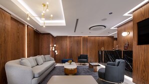 A modern living room with a grey sofa, a white ottoman, a blue armchair, and a round coffee table. - Gleam Collection Hotel (Istanbul)